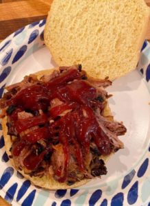 Beef Rib Sandwich being built with a drizzle of bbq sauce.