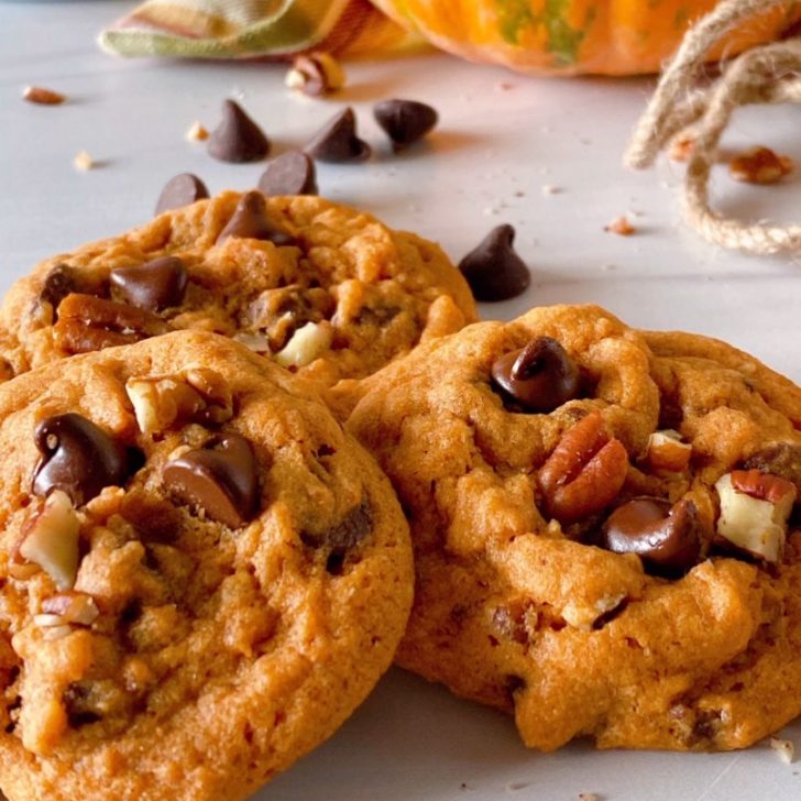 Pumpkin Chocolate Chip Cookies in a stack on a white counter.