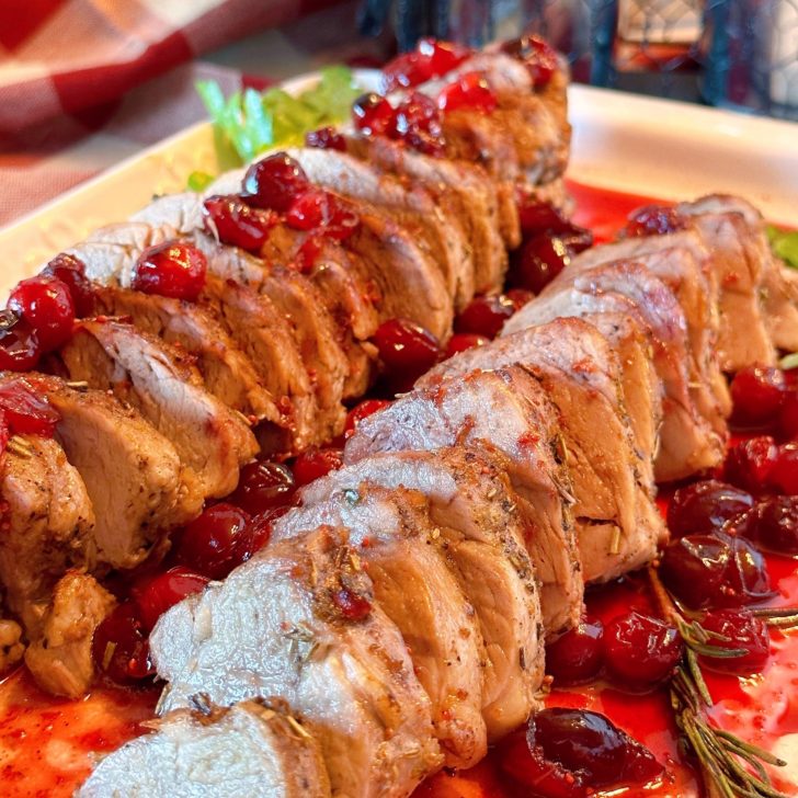 Pork Tenderloin on a serving platter with cranberry sauce.