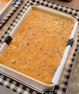 Pan of caramels with nuts added cooling in the baking sheet pan.