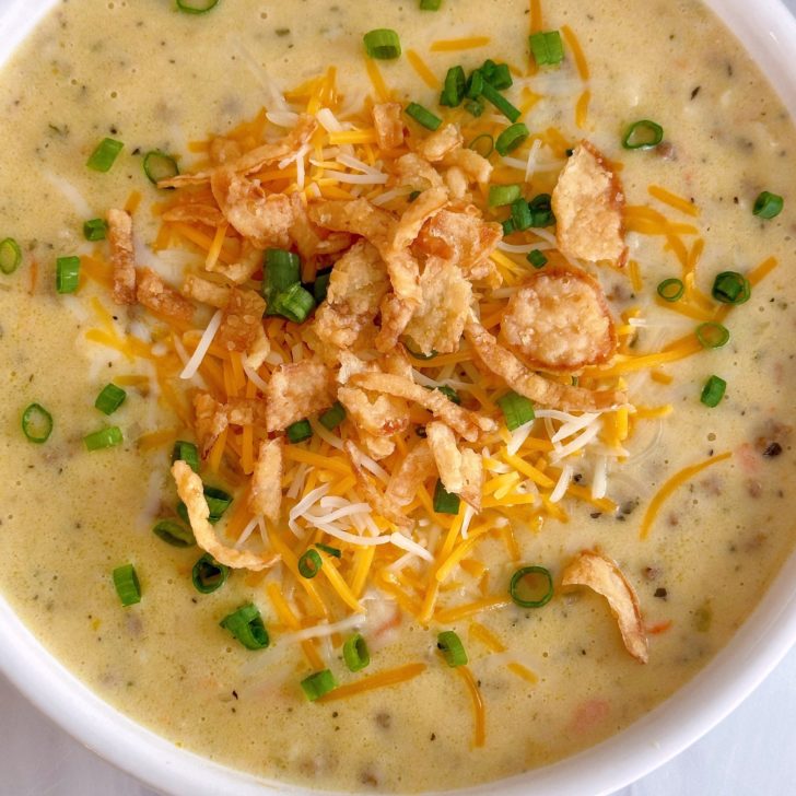 Overhead shot of Cheeseburger soup with toppings of crispy onion rings and green onions.