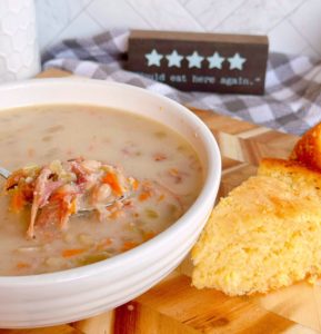 Navy Bean Soup in a white bowl with a slice of cornbread.