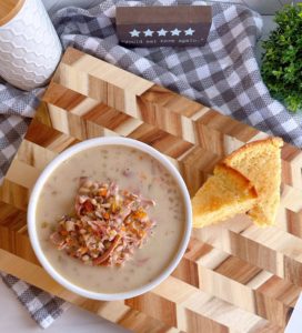 Overhead shot of a bowl of Navy Bean Soup with two slices of cornbread on a cutting board.