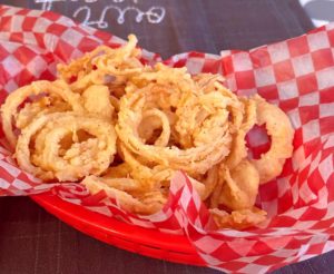 Crispy Onion Straws in a red burger basket with checkered paper.