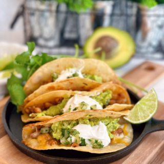 Easy Chicken Tacos with guacamole and sour cream on a skillet.