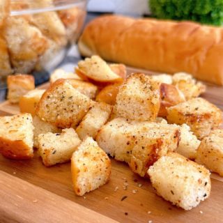 Easy Homemade Croutons on a wooden cutting board with a loaf of bread.