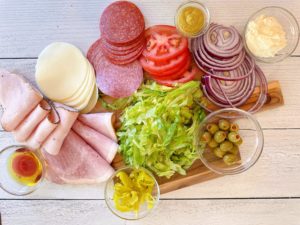 Italian Grinder Sandwich ingredients on a white cutting board.