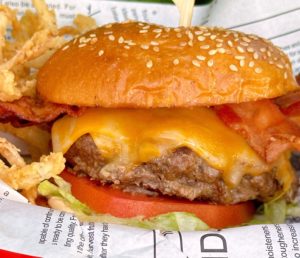 Ultimate Bacon Smash Cheeseburger in a red basket with onion straws.