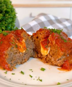 Individual Italian Meatloaf cut in half revealing melted cheese stuffed in the center.