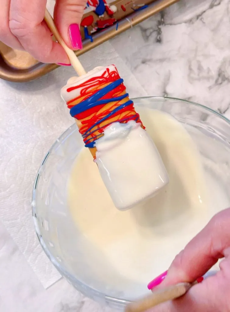 Dipping each cake pop of top in melted white chocolate.