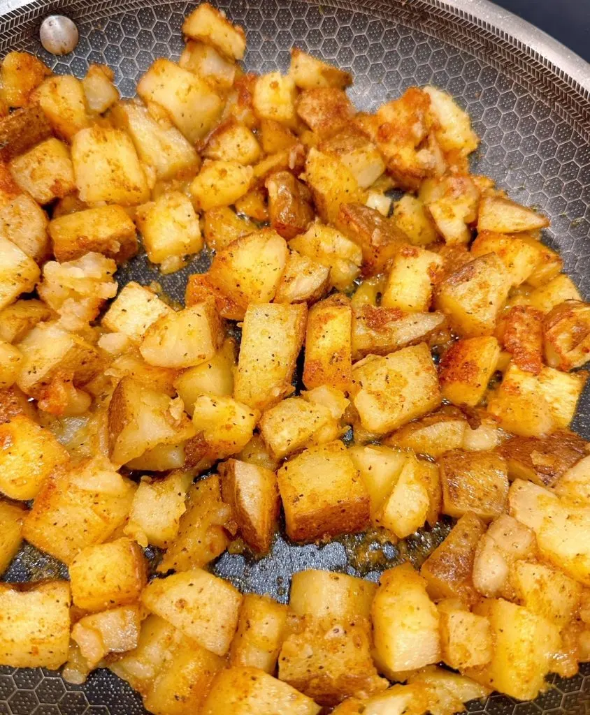 Skillet potatoes in a frying pan, cooking over the stove.