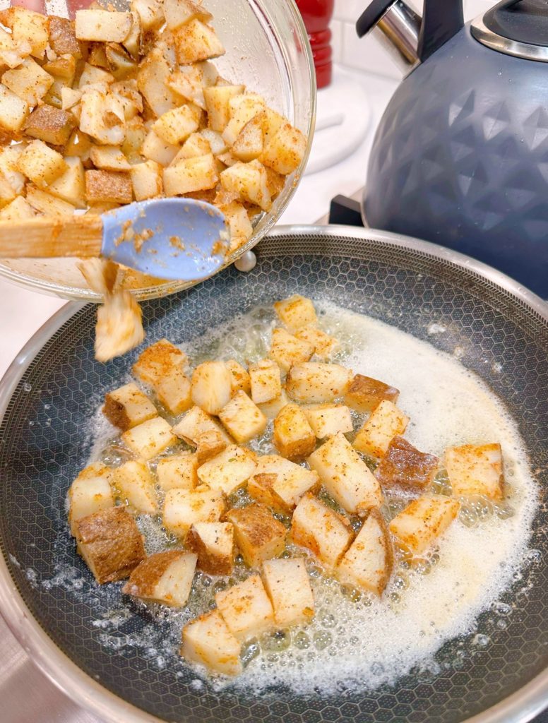 Adding seasoned potatoes to hot skillet with melted butter.