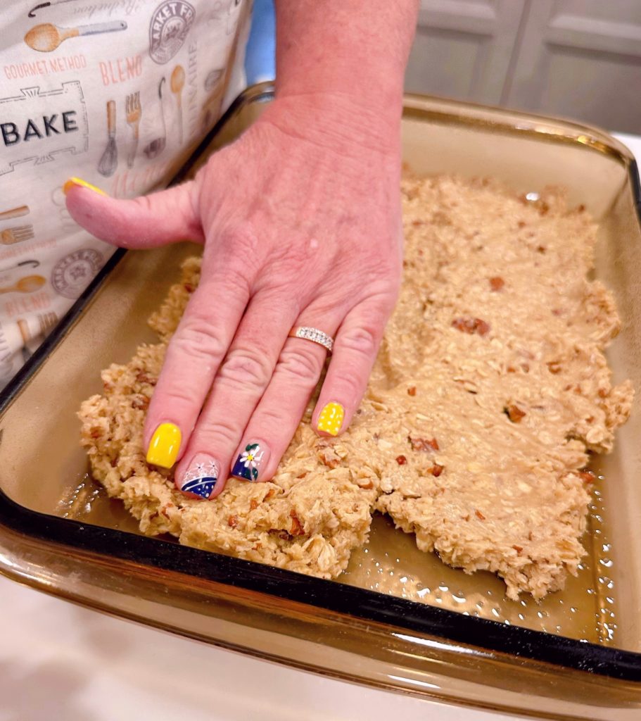 Pressing oat mixture into the bottom of the pan.