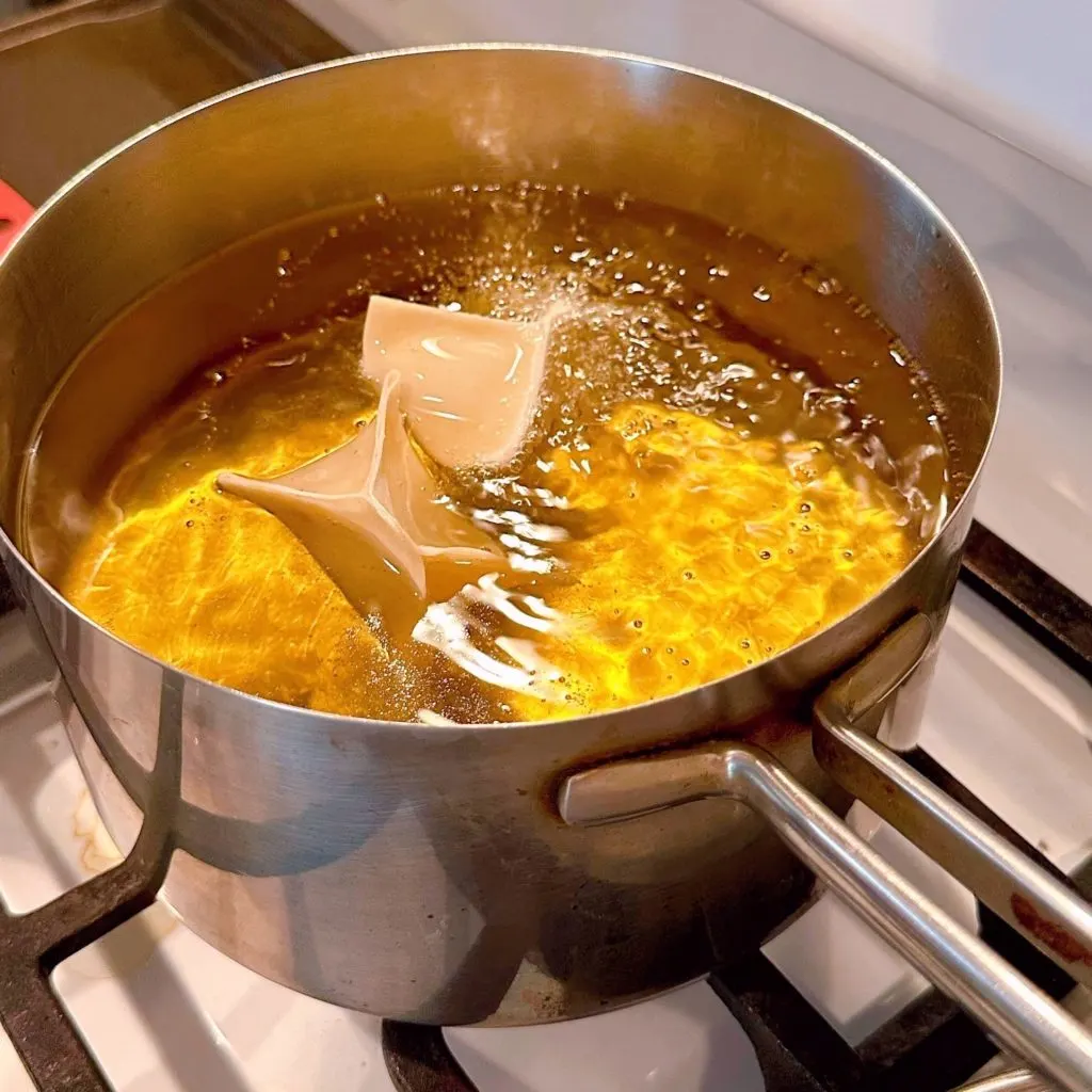 Frying wonton apple pies in hot oil over medium high heat.