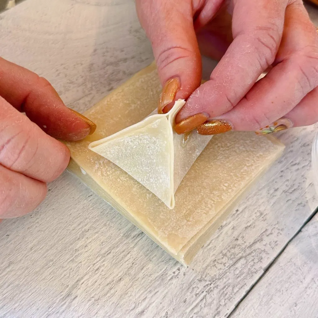 Pinching down the seams from the top of each wonton.