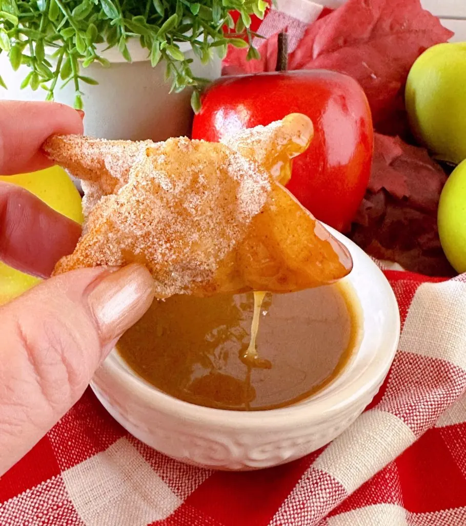 Dipping apple pie bite in caramel sauce.