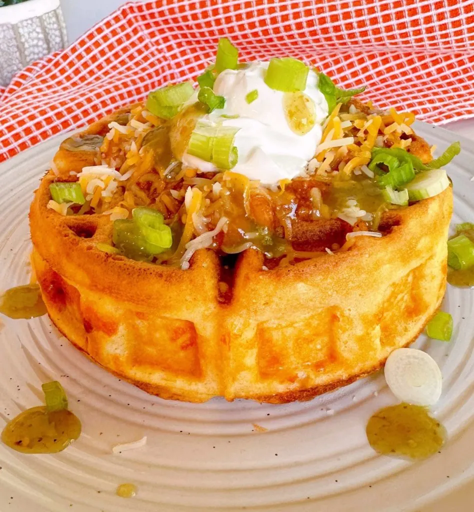 Chili Stuffed Cornbread Waffle topped with sour cream, cheese, and green onions. 