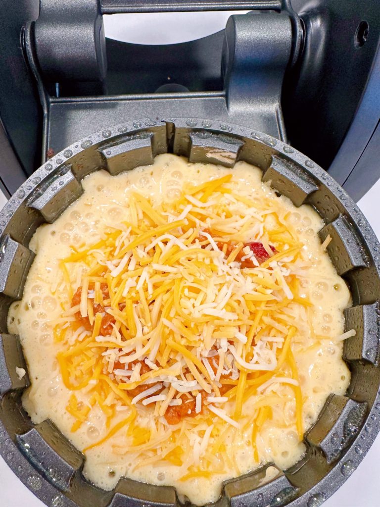 More cheese on top of the chili in the waffle iron.