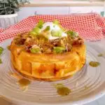 Stuffed Cornbread waffle with chili and cheese. Topped with sour cream, chives, and hot sauce.