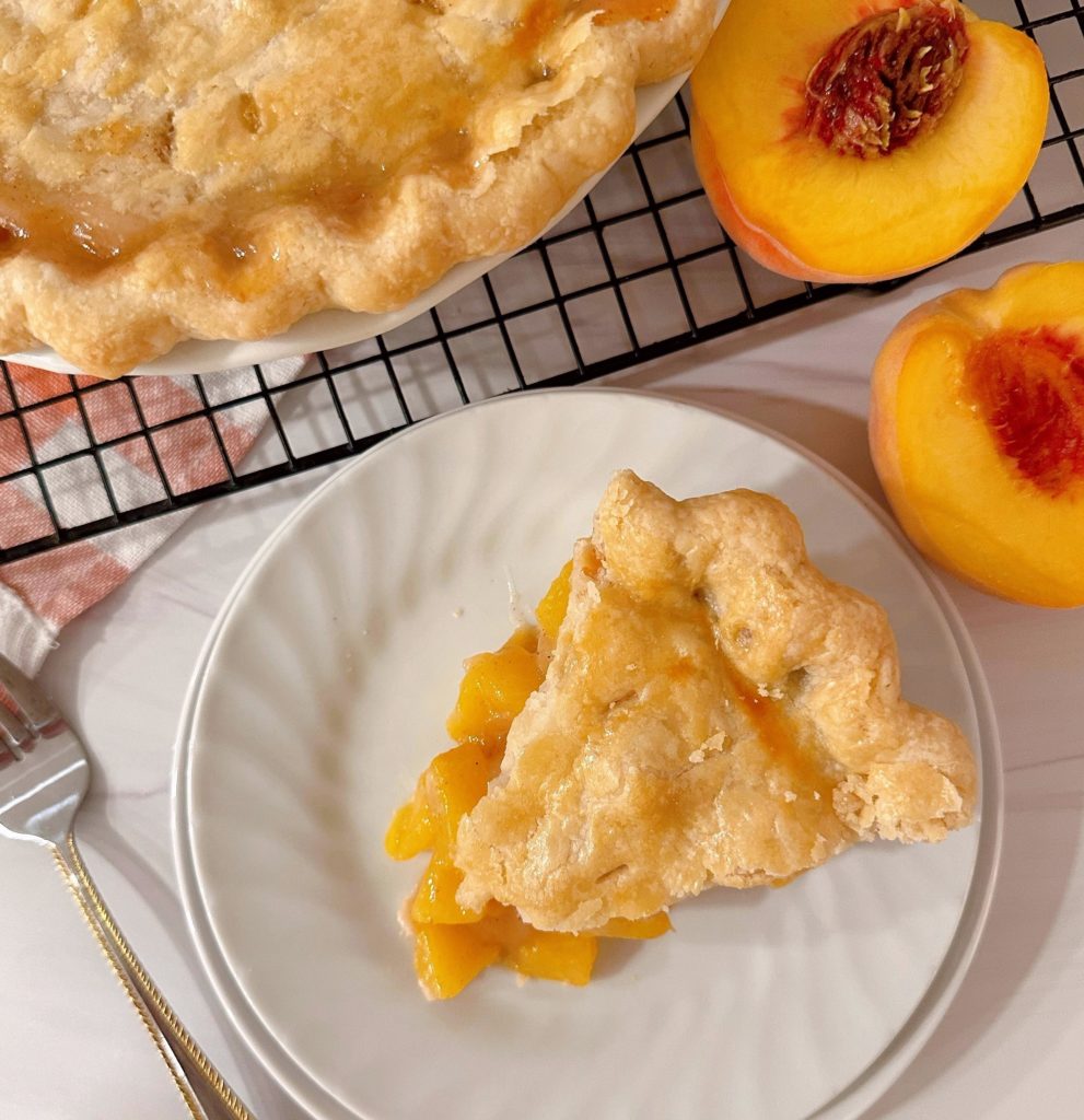 Peach pie sliced and on a serving dish with a fork.