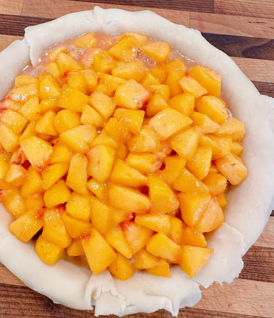 Filling the pie crust with peach pie filling.