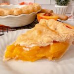 Fresh Peach Pie sliced and on a white plate.