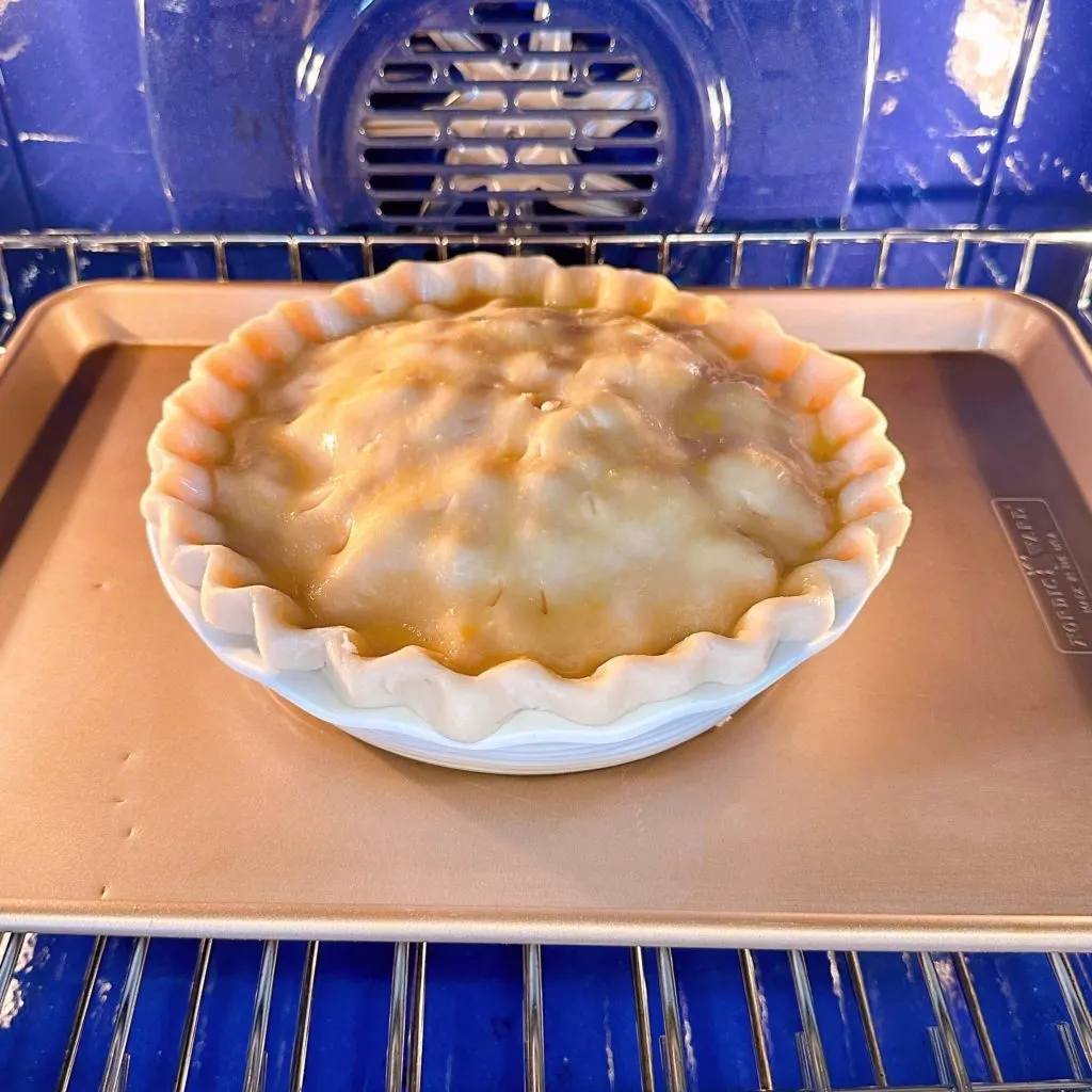 Peach pie in the oven on a baking sheet.