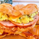 Close-up of egg croissant sandwich with cheese and canadian bacon.