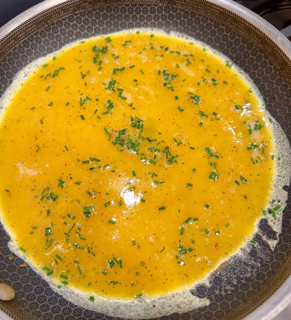 Cooking scrambled eggs in a large skillet over medium heat.