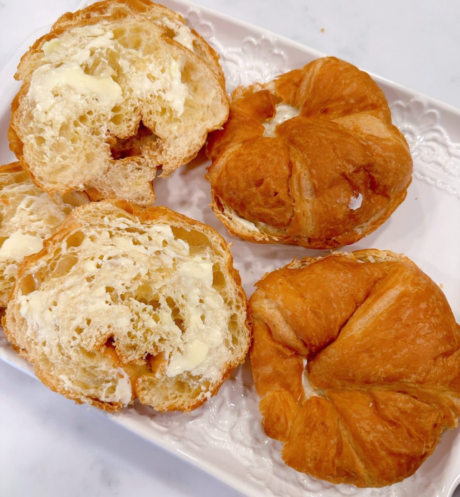 Buttered croissant buns on a platter waiting to be toasted.