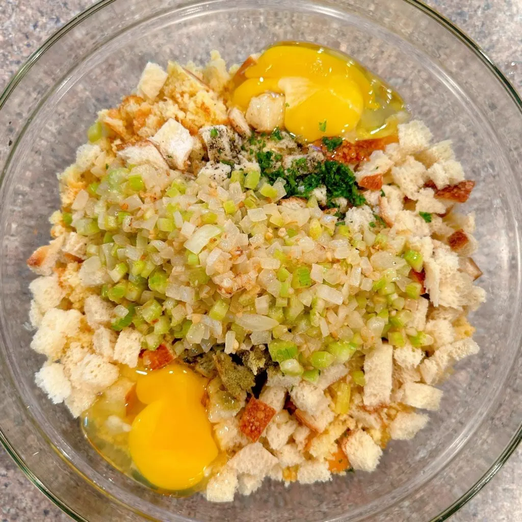 Adding sauteed ingredients, eggs, and chicken stock to cornbread dressing.