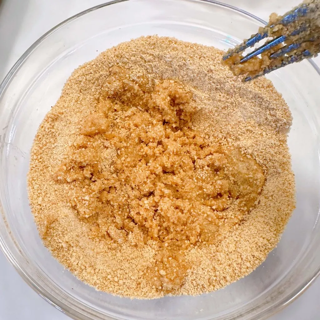 Mixing butter in graham cracker mixture for crust.