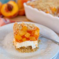 Layered Peach Delight Dessert sliced and on a plate with a fork.