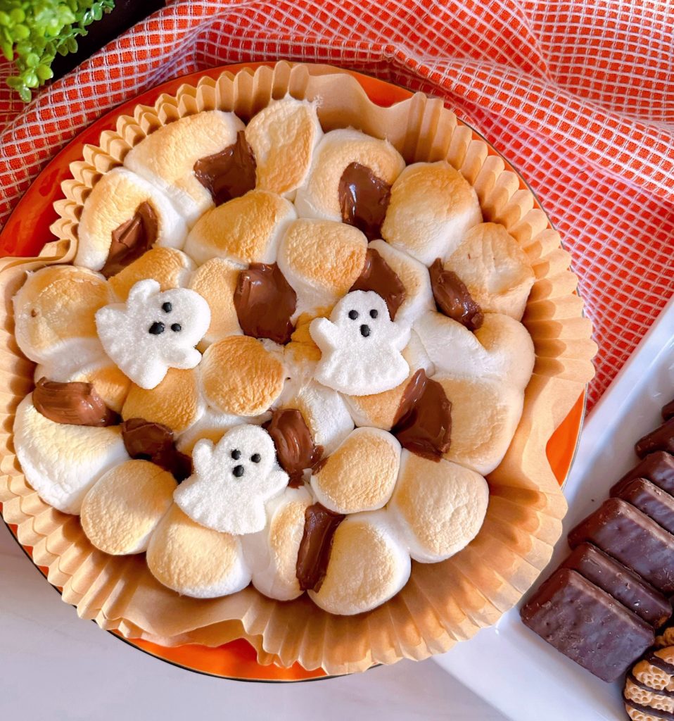 S'mores air fryer dip in a halloween dish with cookies and crackers for dipping.