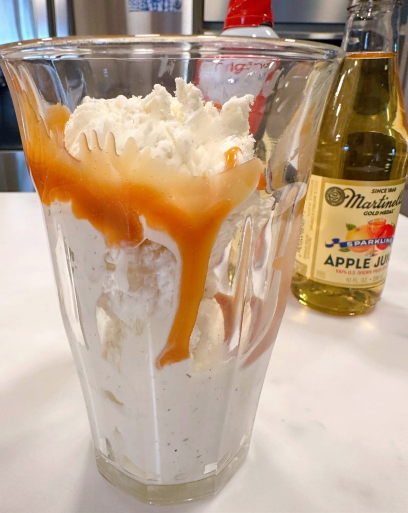 Drizzled caramel and scoops of ice cream in a large glass.