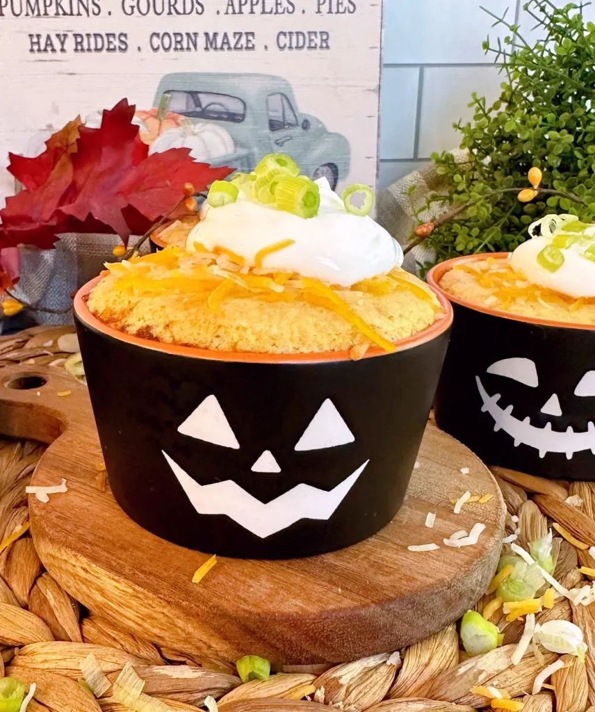 Individual chili cornbread cup topped with sour cream and sliced onions.