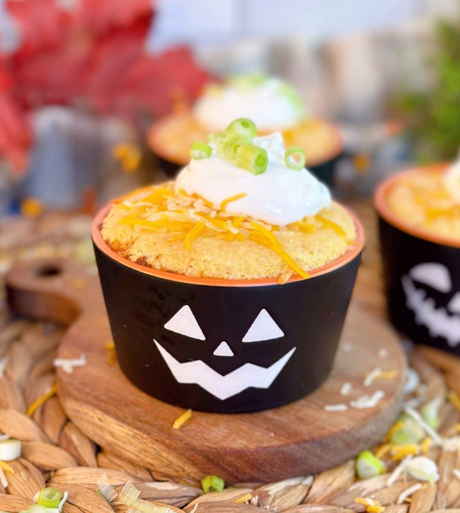 Chili Cornbread Cup filled with chili and topped with a cornbread muffin top, cheese, sour cream, and green onions in a fun Halloween ramakin.