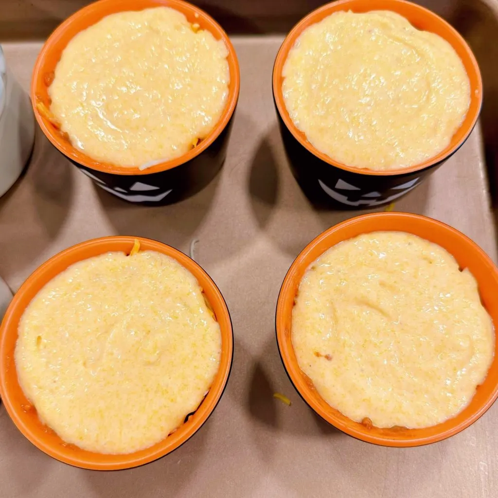 Cornbread spread to edges of ramekin cups.