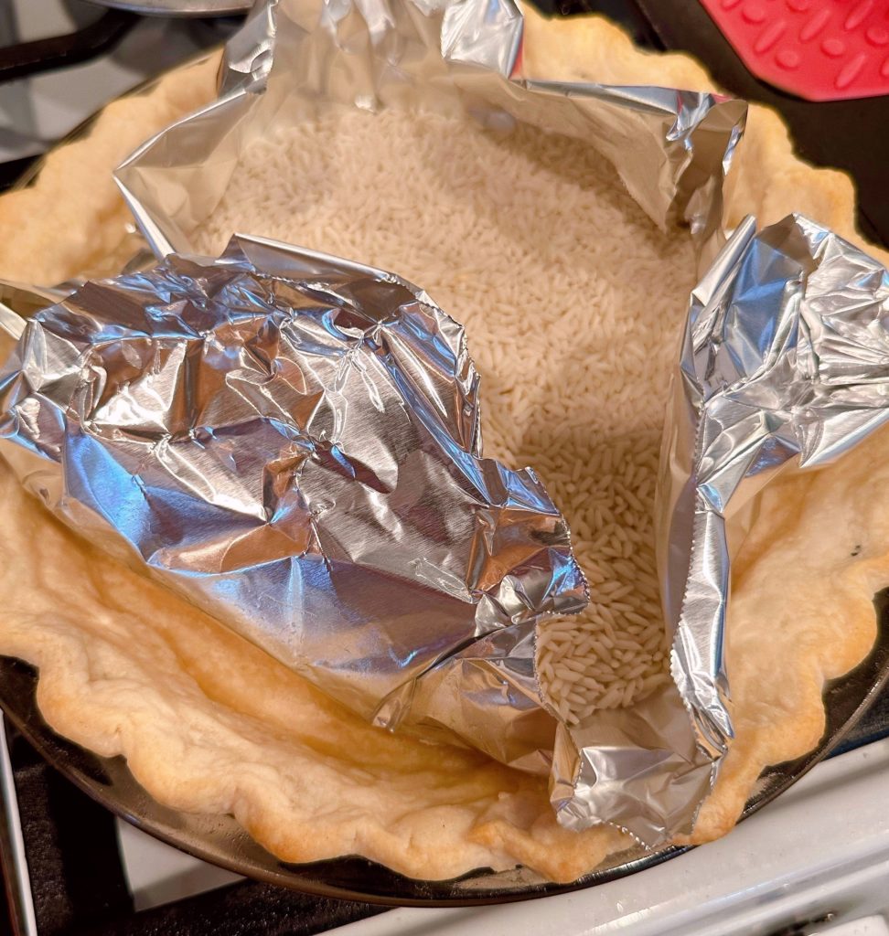 The pie crust is pre-baked and cooled on a rack.