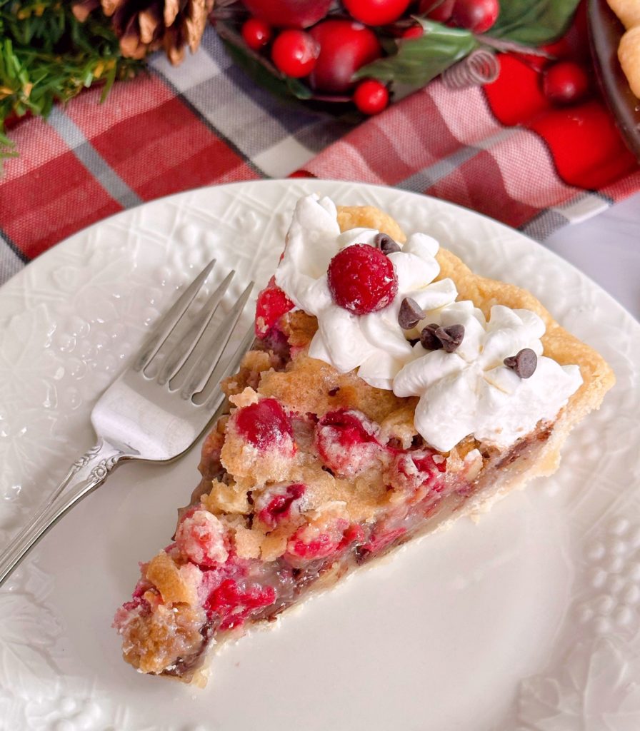 Slice of cranberry walnut chocolate pie on a white plate with a fork.