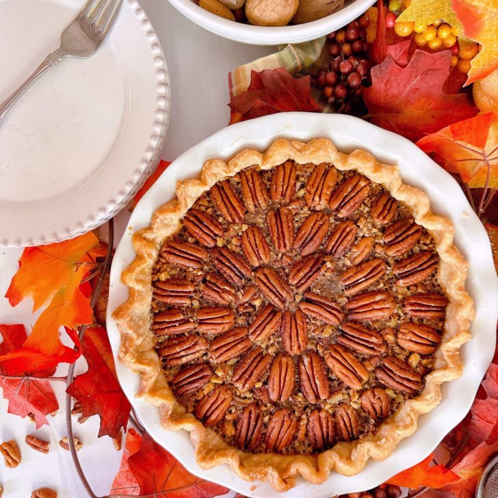 Pecan Pie with serving plates and fall foliage.