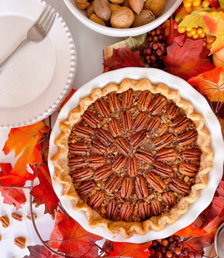 Pecan Pie with serving plates and fall foliage.