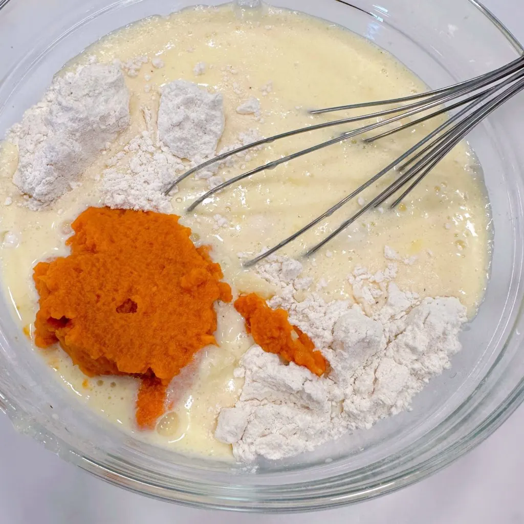 Adding pumpkin puree to pancake batter.