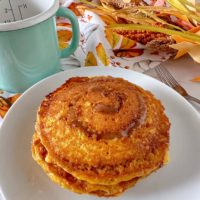 Pumpkin Spice Cinnamon Roll Buttermilk Pancakes stacked on a white palte.