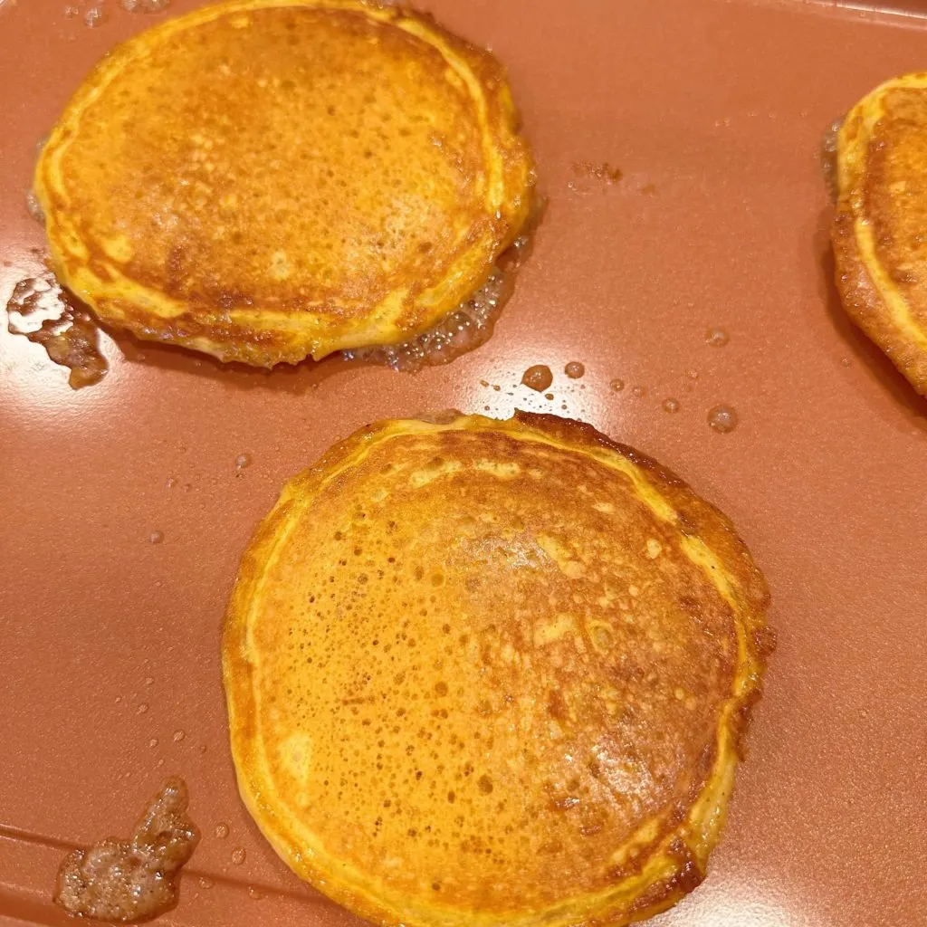 Pumpkin pancakes with cinnamon swirl baking on the griddle.