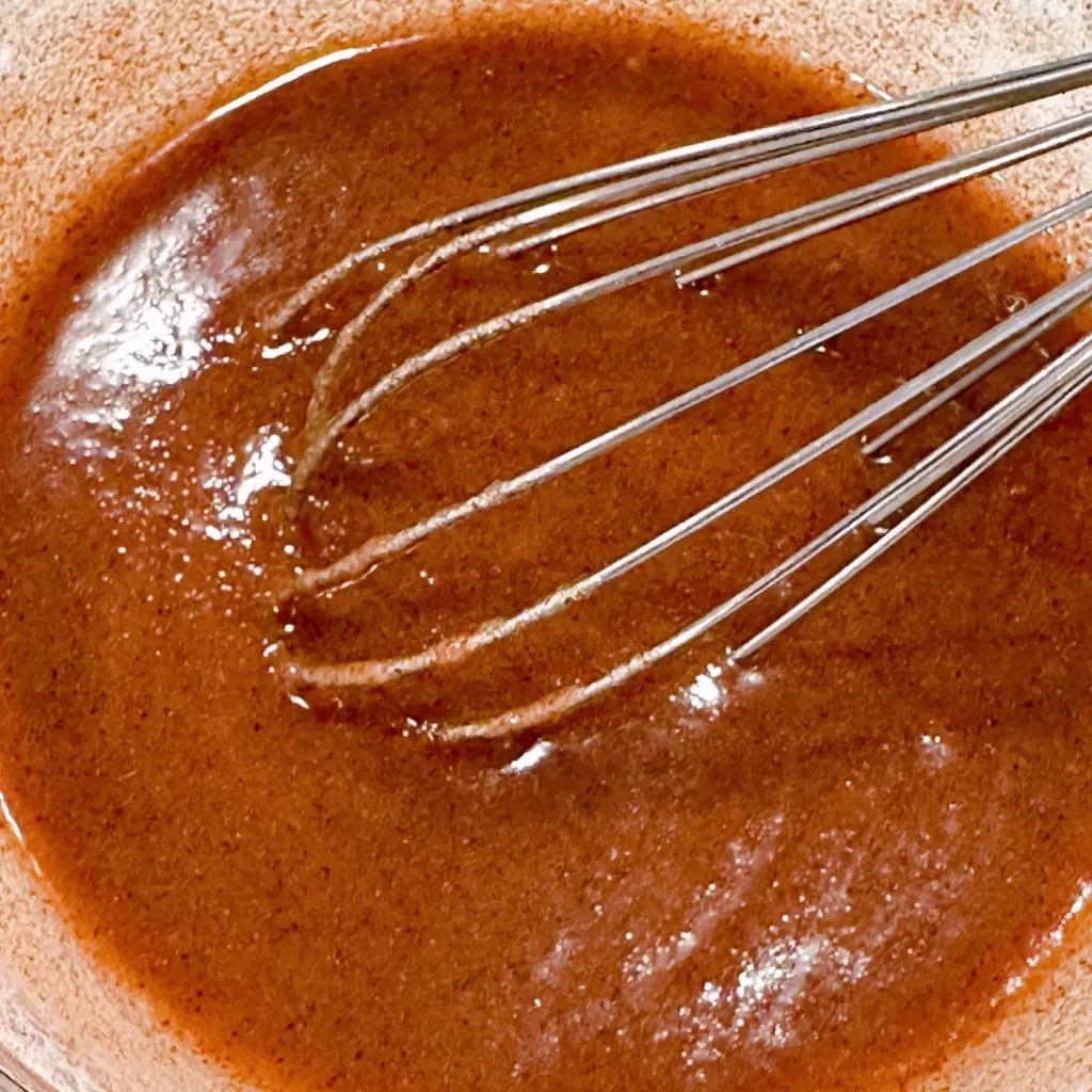 Cinnamon filling in a bowl with a wire whisk.