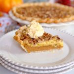 Slice of pumpkin crunch pie on a dessert plate with the rest of the pie in the background.