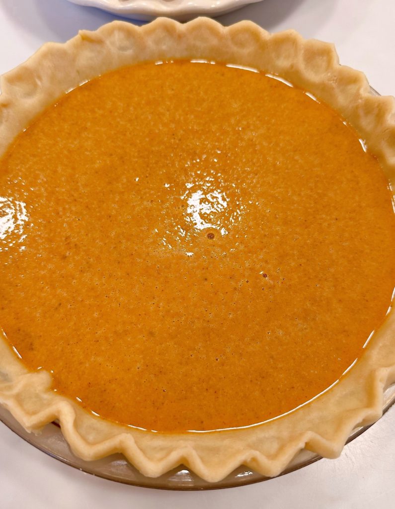 Pumpkin filling poured into a pie shell.