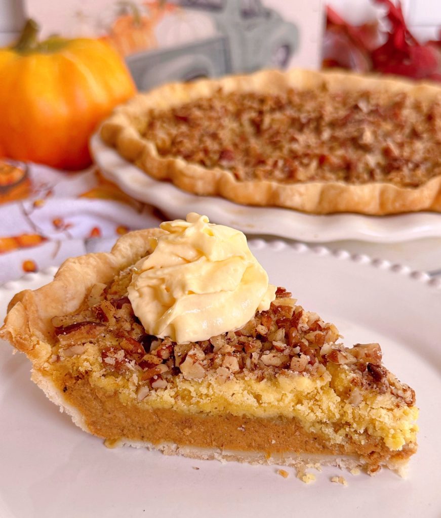 Pumpkin crunch pie sliced and topped with whipped cream with the whole pie in the background.