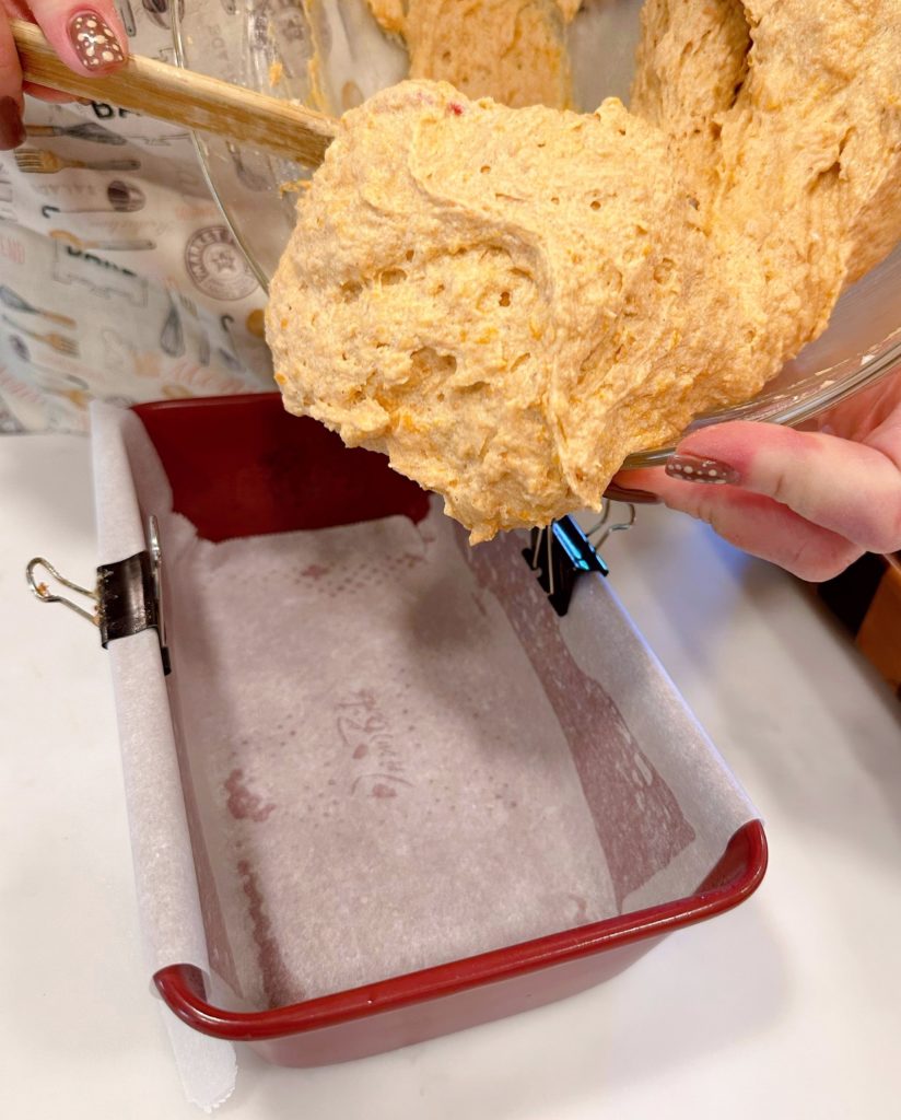 Pouring sweet potato batter into loaf pan.